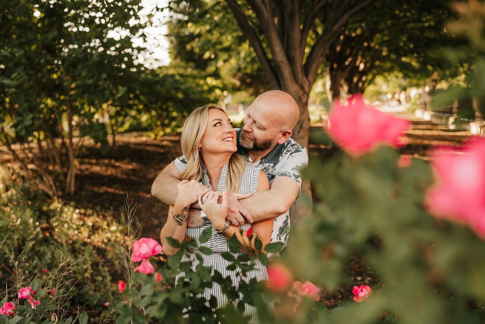 husband hugs wife near rose bushes in Washington park in cincinnati