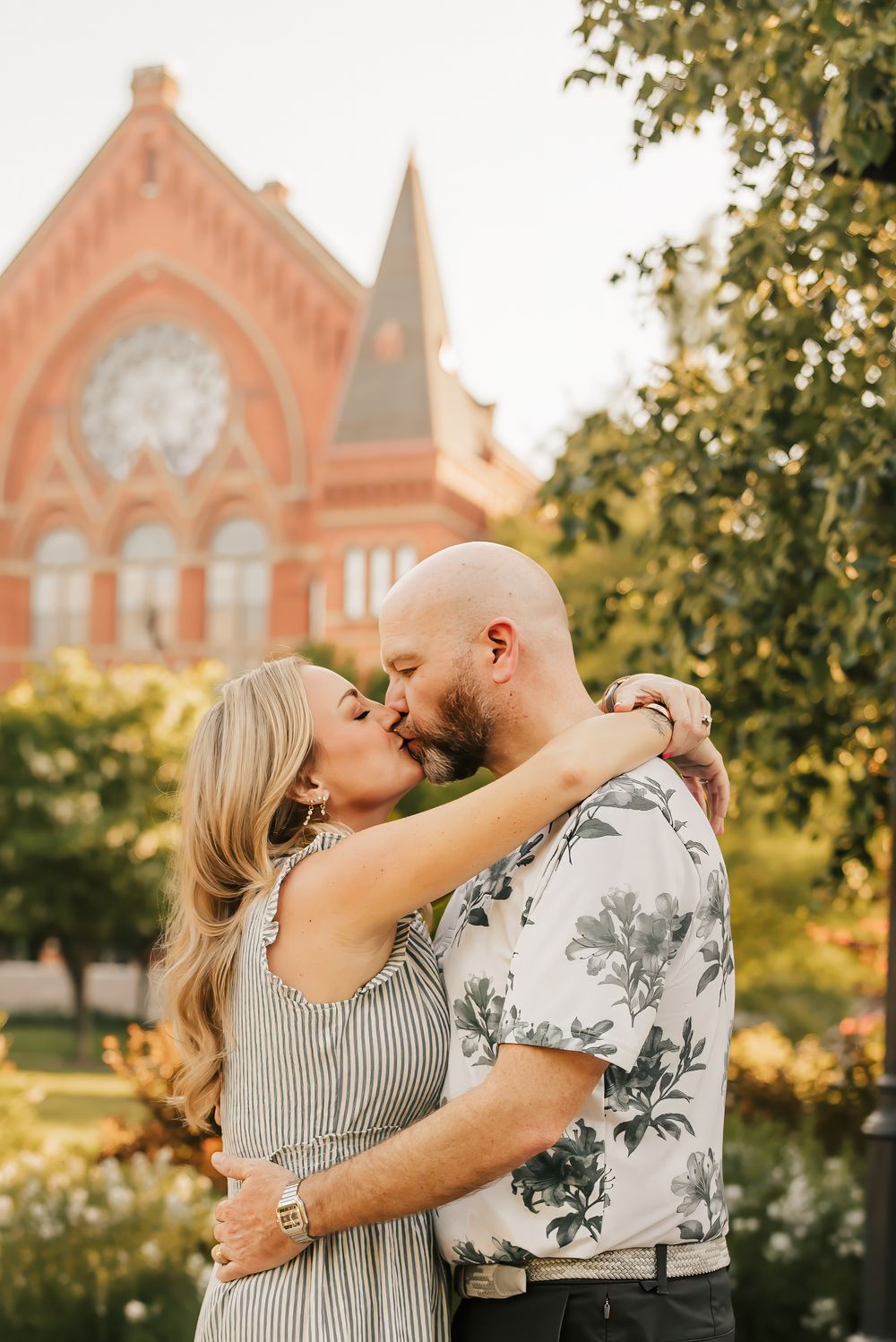 couple kisses in Washington park overlooking music hall in cincinnati, ohio