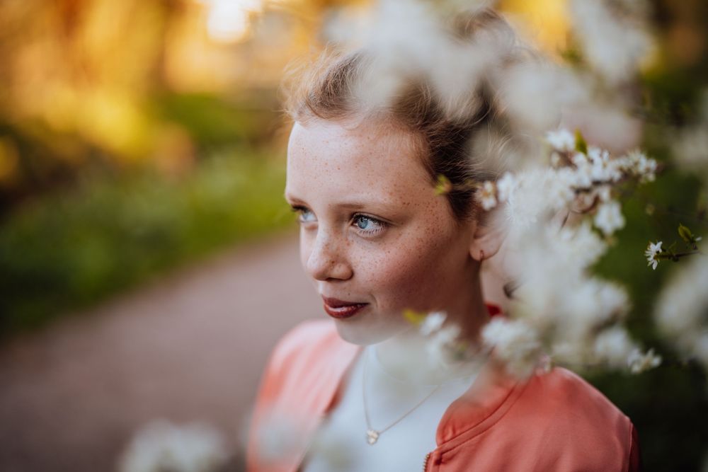 Lenteportret met witte bloesems en warm avondzonlicht in een tuin.