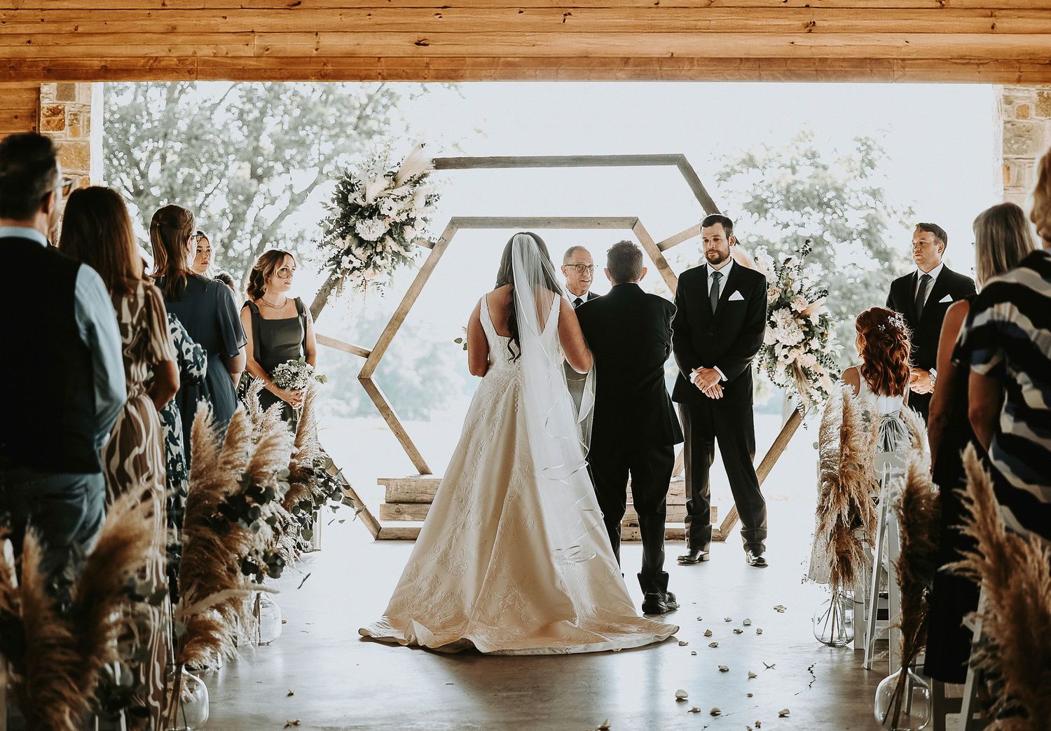 Bride walking down the aisle under wooden beam pavilion