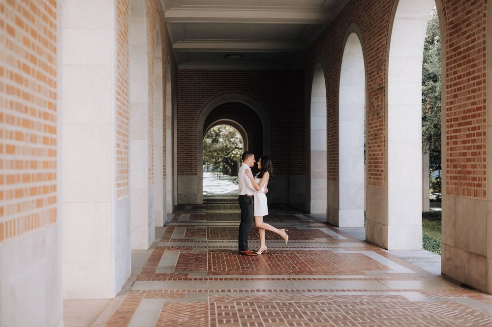 A serene brick archway corridor with someone standing on decorative floor tiles.