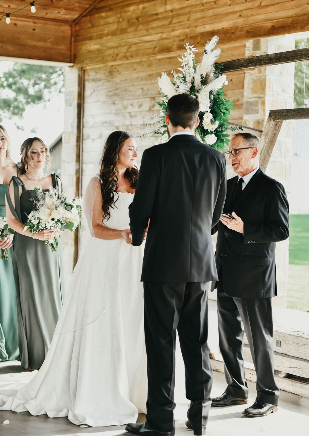 bride and groom stand in front of their boho altar in front of their wedding officient