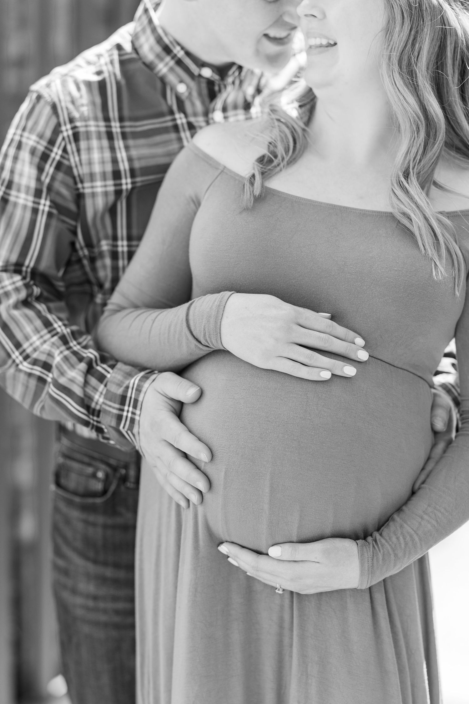 Black and white photo of a couple sharing an intimate pregnancy moment with hands lovingly placed on her baby bump at Chicago Botanic Garden