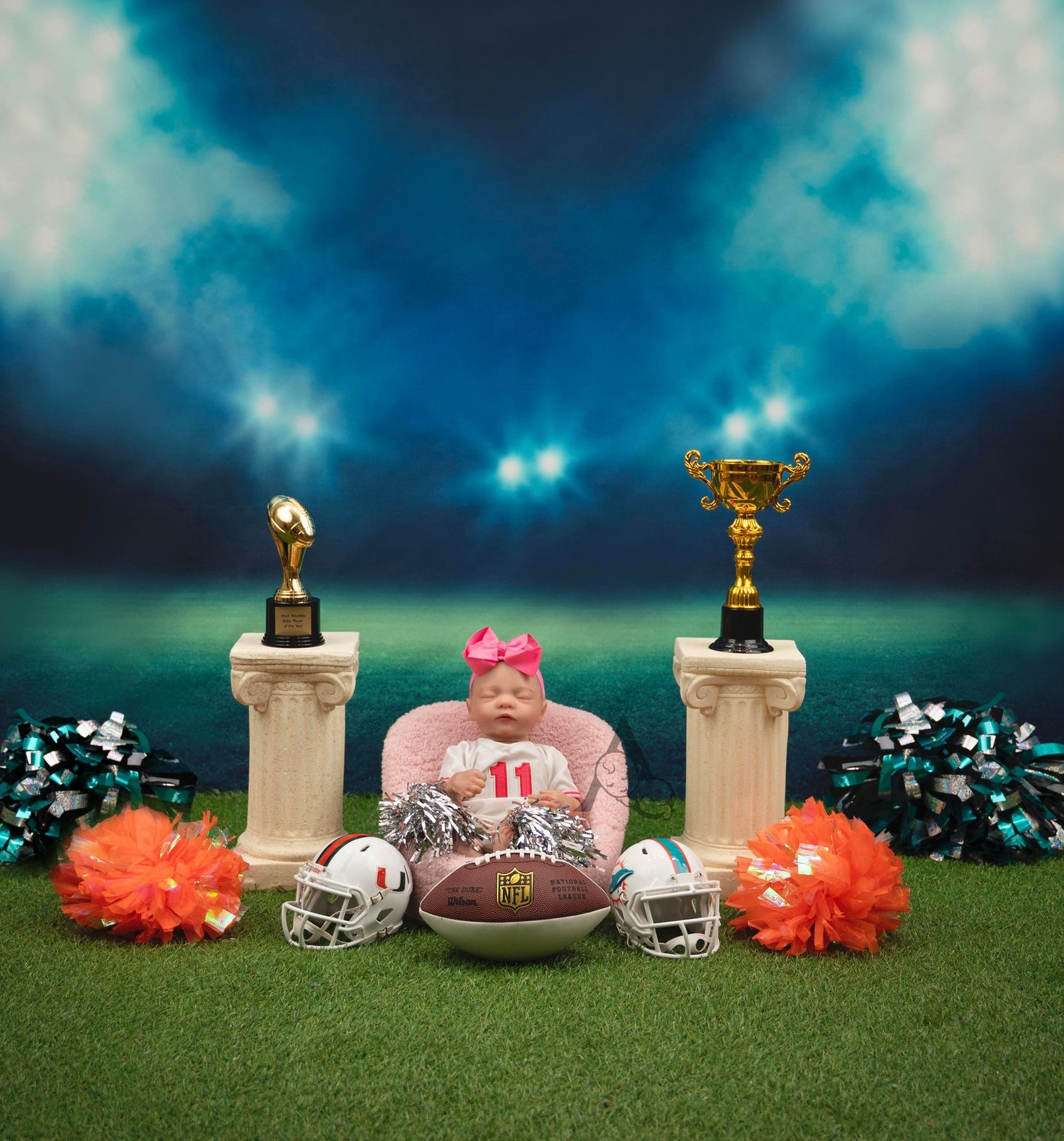 Sports-themed still life with trophies, football, and orange pom poms against a dramatic night sky backdrop.