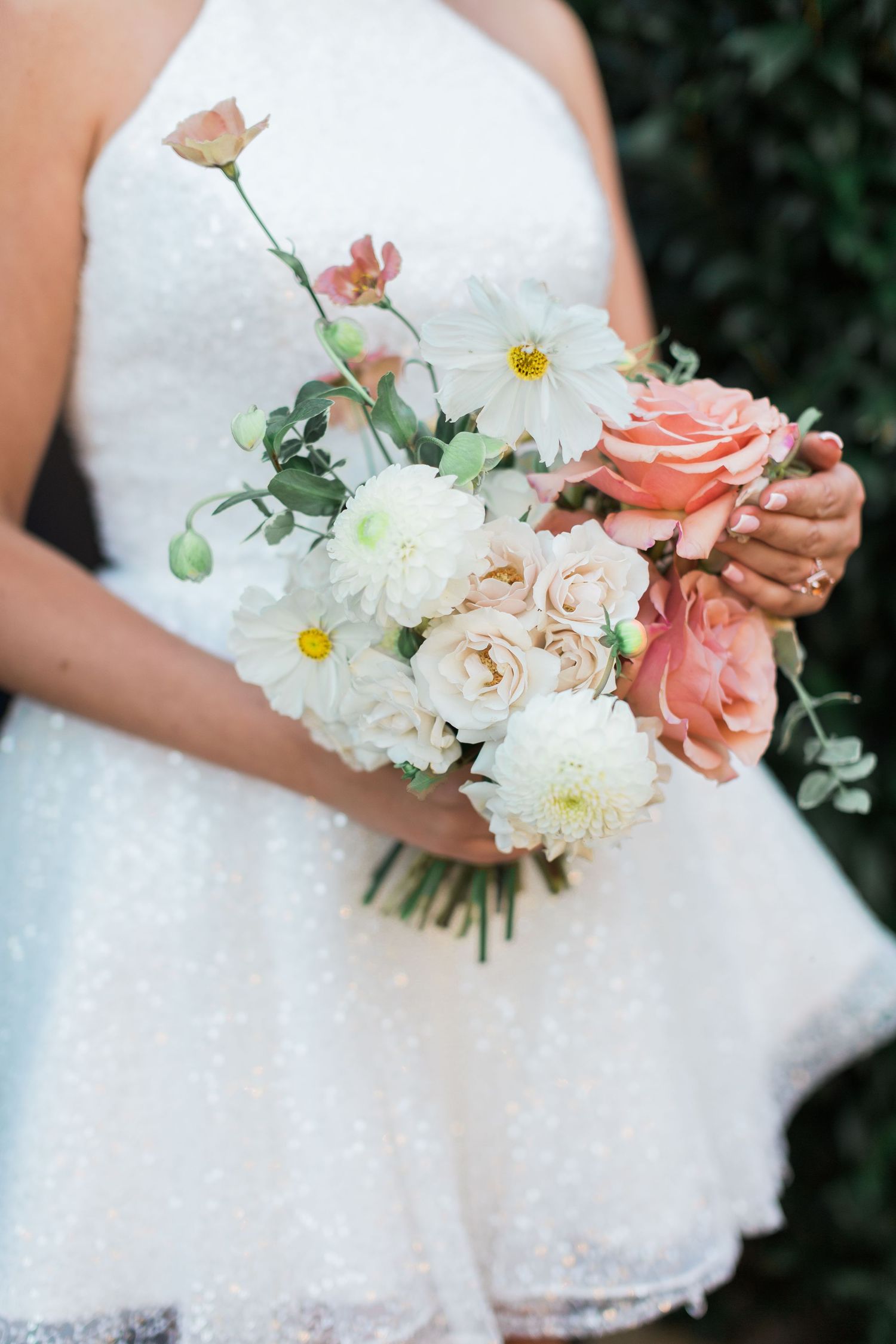 Bride in white sparkling dress holding romantic bouquet with coral roses, white dahlias and eucalyptus greenery by Hayley Elizabeth