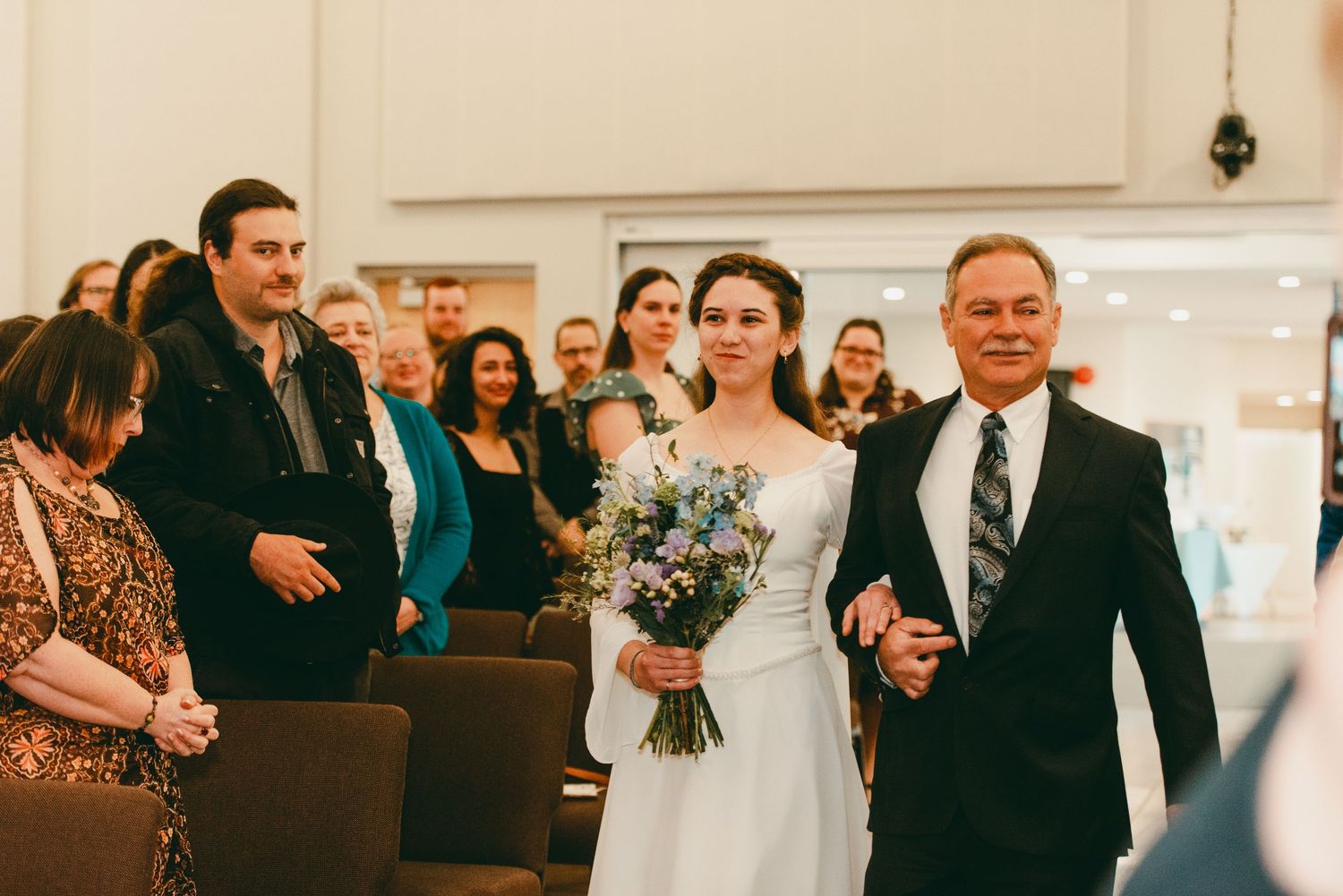 Bride and father of bride walk down the aisle happily as she looks at her new husband
