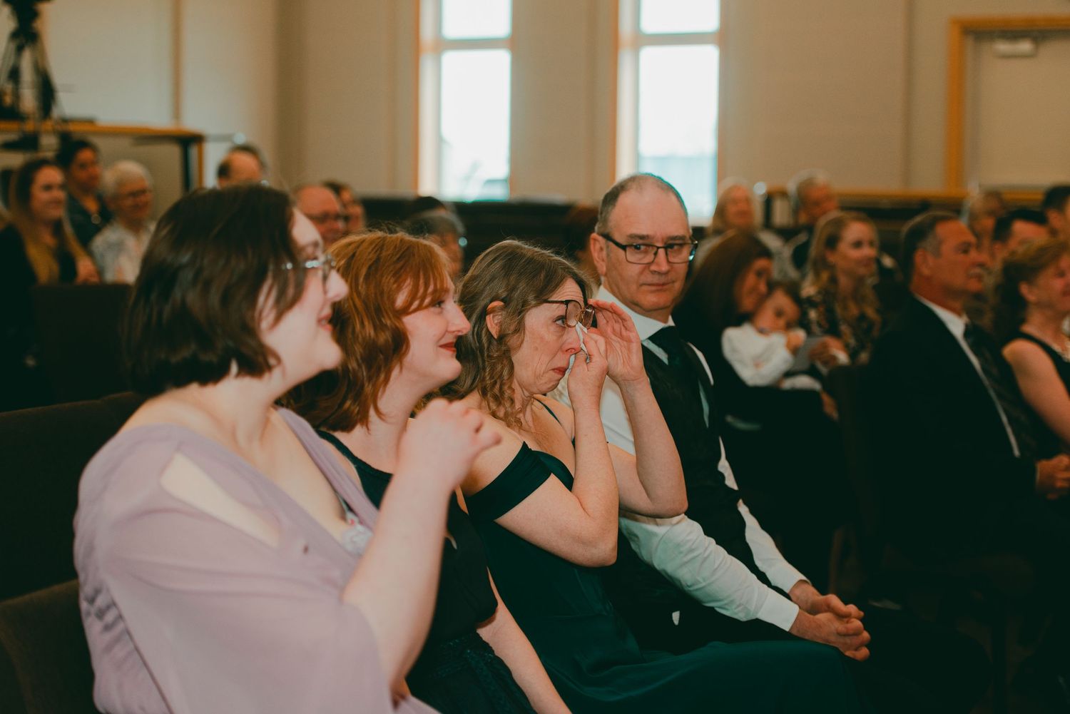 Family of groom as the mother of groom cries during groom's personal vows to bride