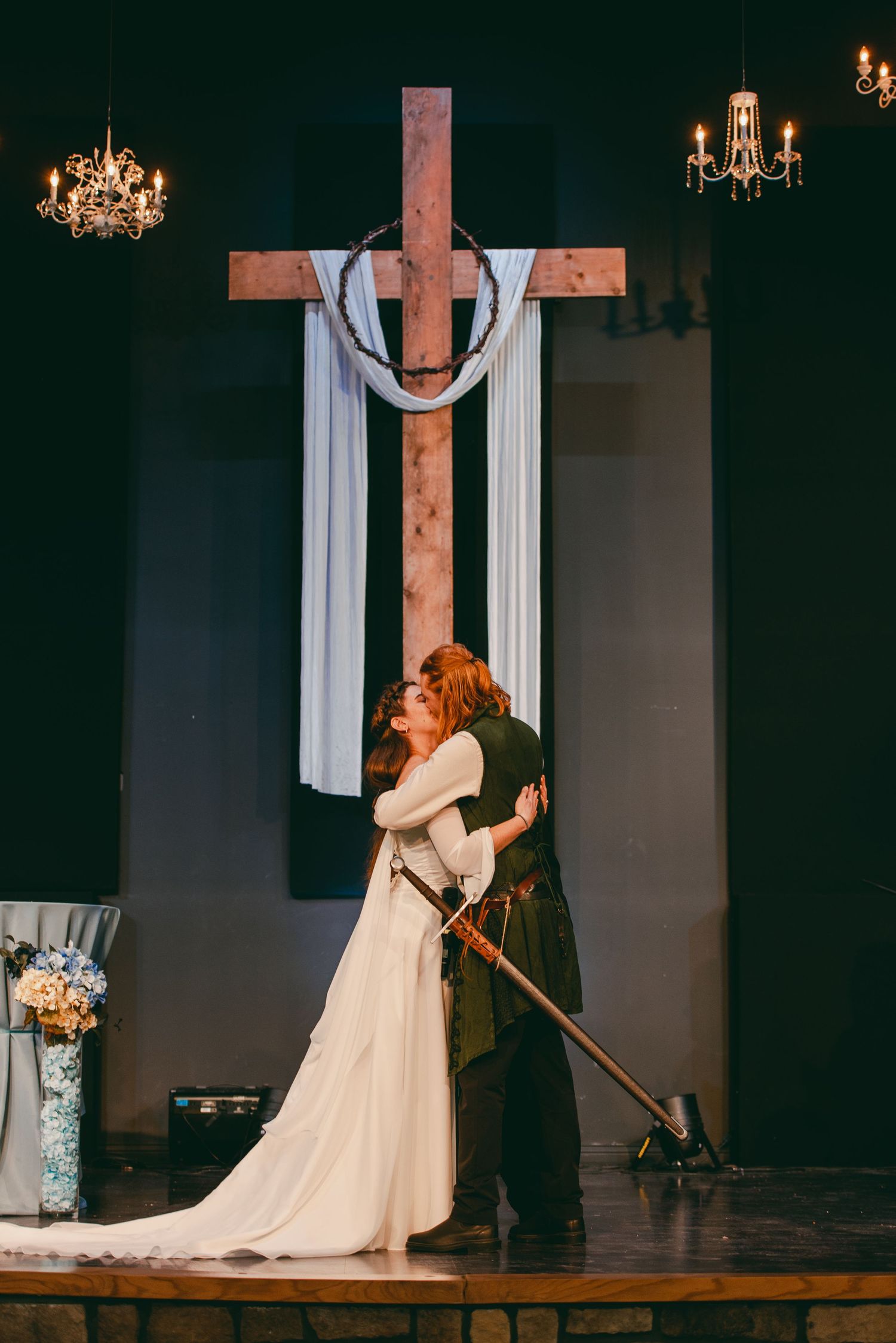 Bride and groom kissing at wedding ceremony in front of cross