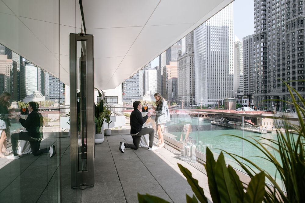 People relaxing on a modern high-rise balcony overlooking a cityscape with glass buildings and urban architecture.