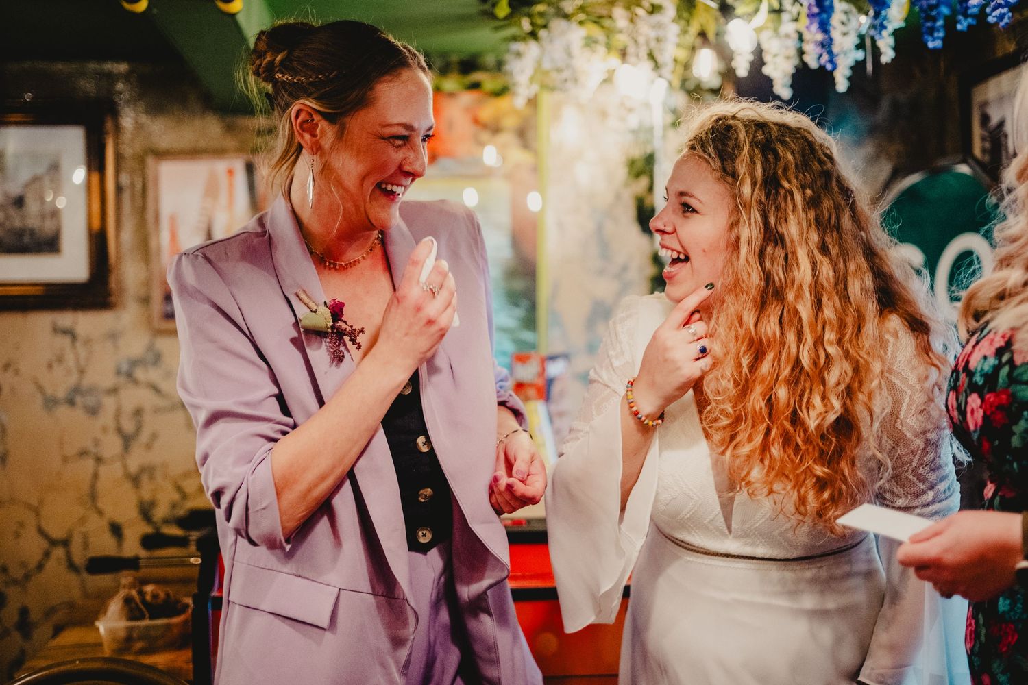 Two people sharing a joyful moment of laughter together at an indoor celebration event.