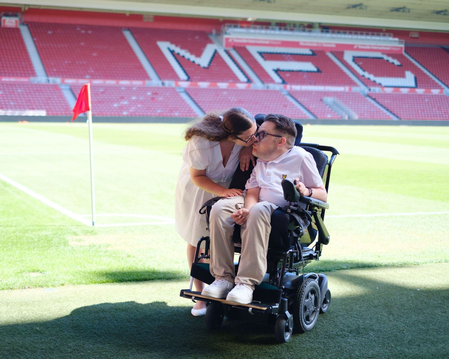 Lucy and Owen sharing a cheeky kiss, pitch side.