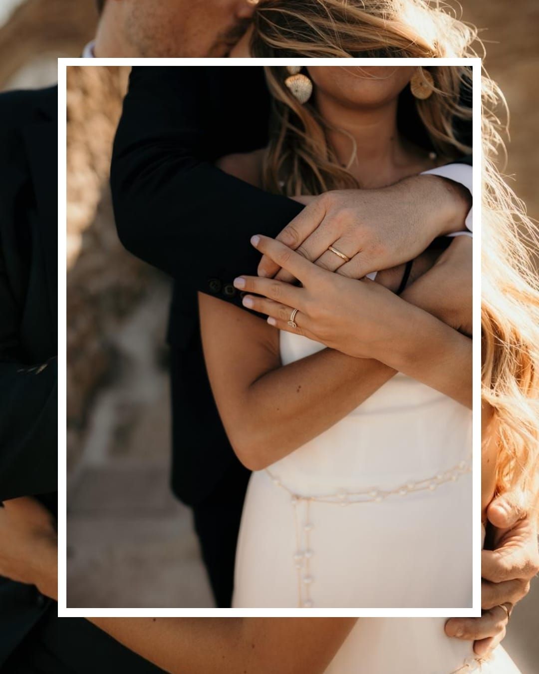 Close-up romantic photo showing hands with engagement rings embracing in golden sunlight.