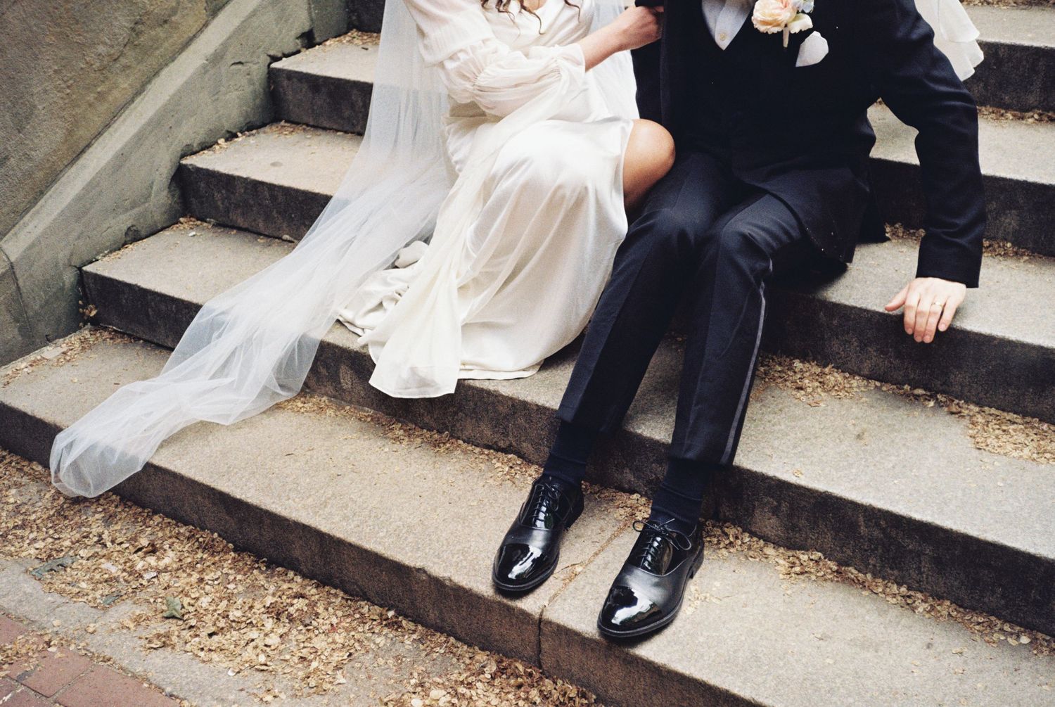 Romantic wedding photo showing bride and groom's legs sitting on concrete steps.