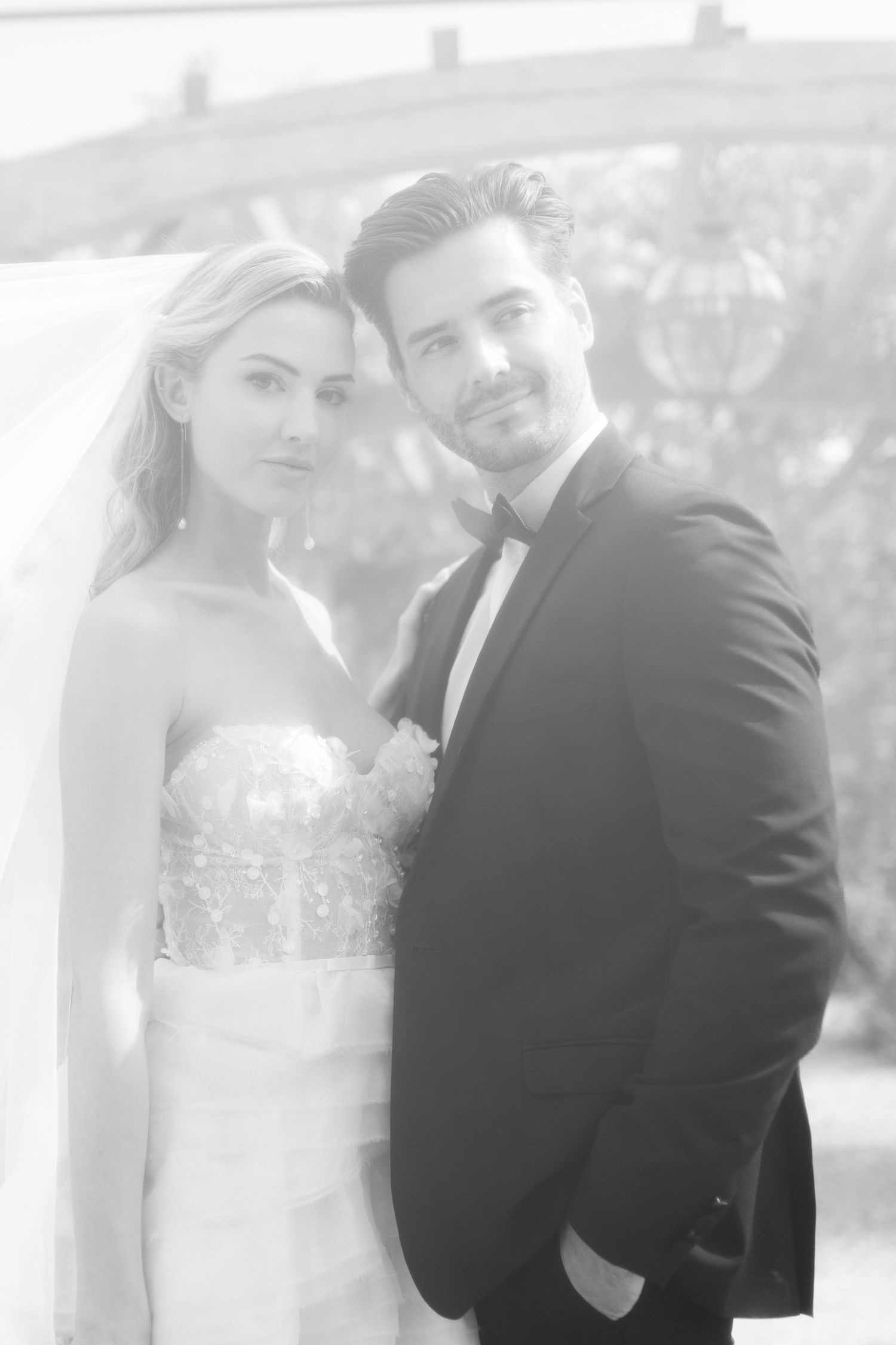 A bride in a strapless wedding gown and groom in classic tuxedo pose together in soft black and white photography by Hayley Eliz at Euridge