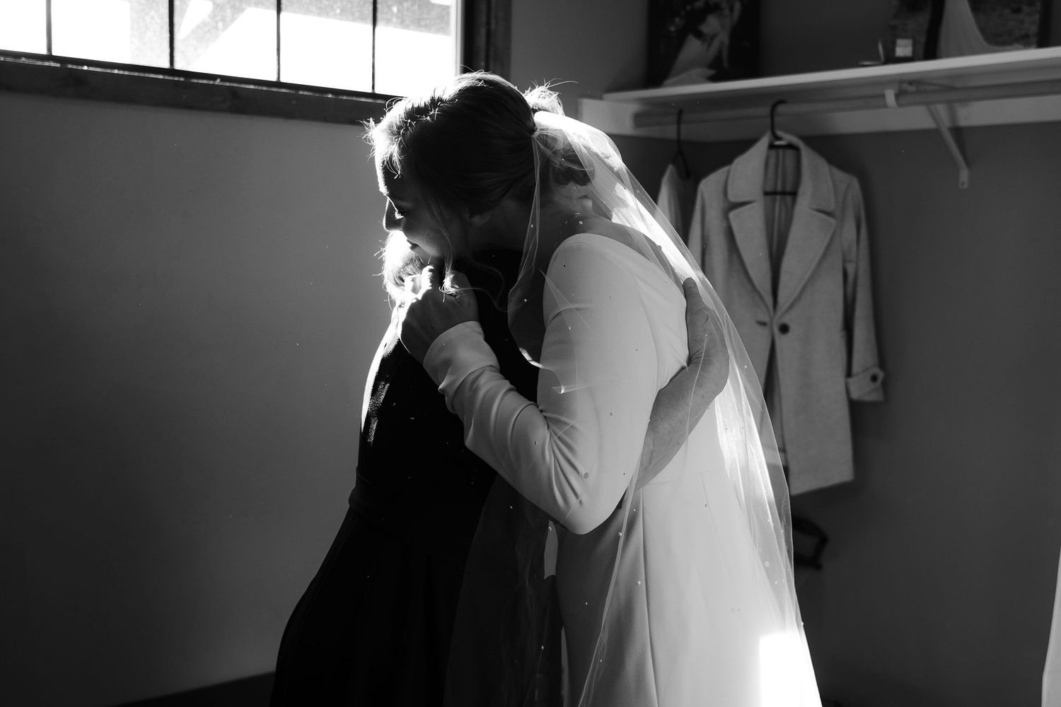 A touching black and white moment captured during an embrace between a couple in formal wedding attire.