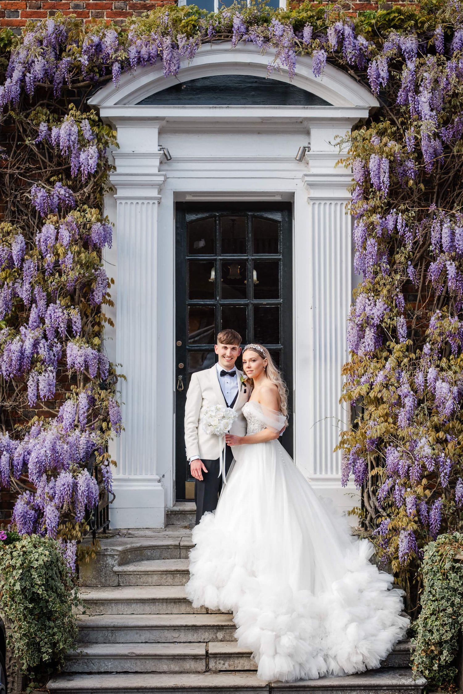 bride and groom pose in wisteria arch at the orangery in Maidstone kent