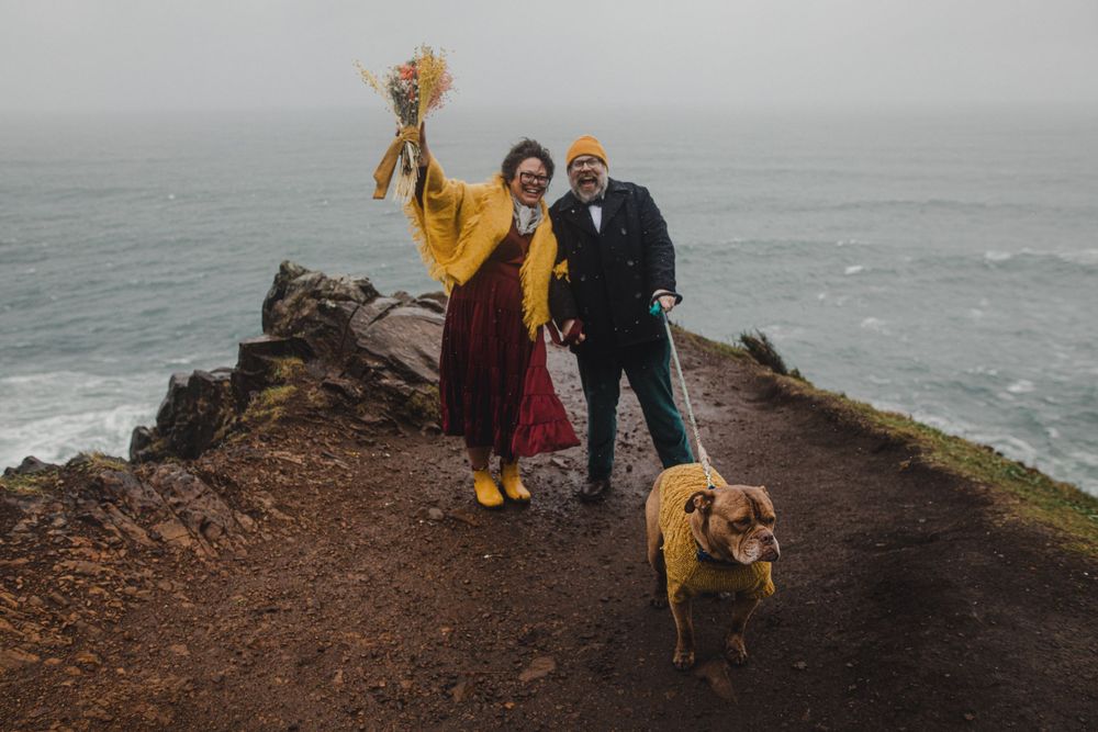 A cheerful moment on a coastal cliff path with a couple and their golden retriever.