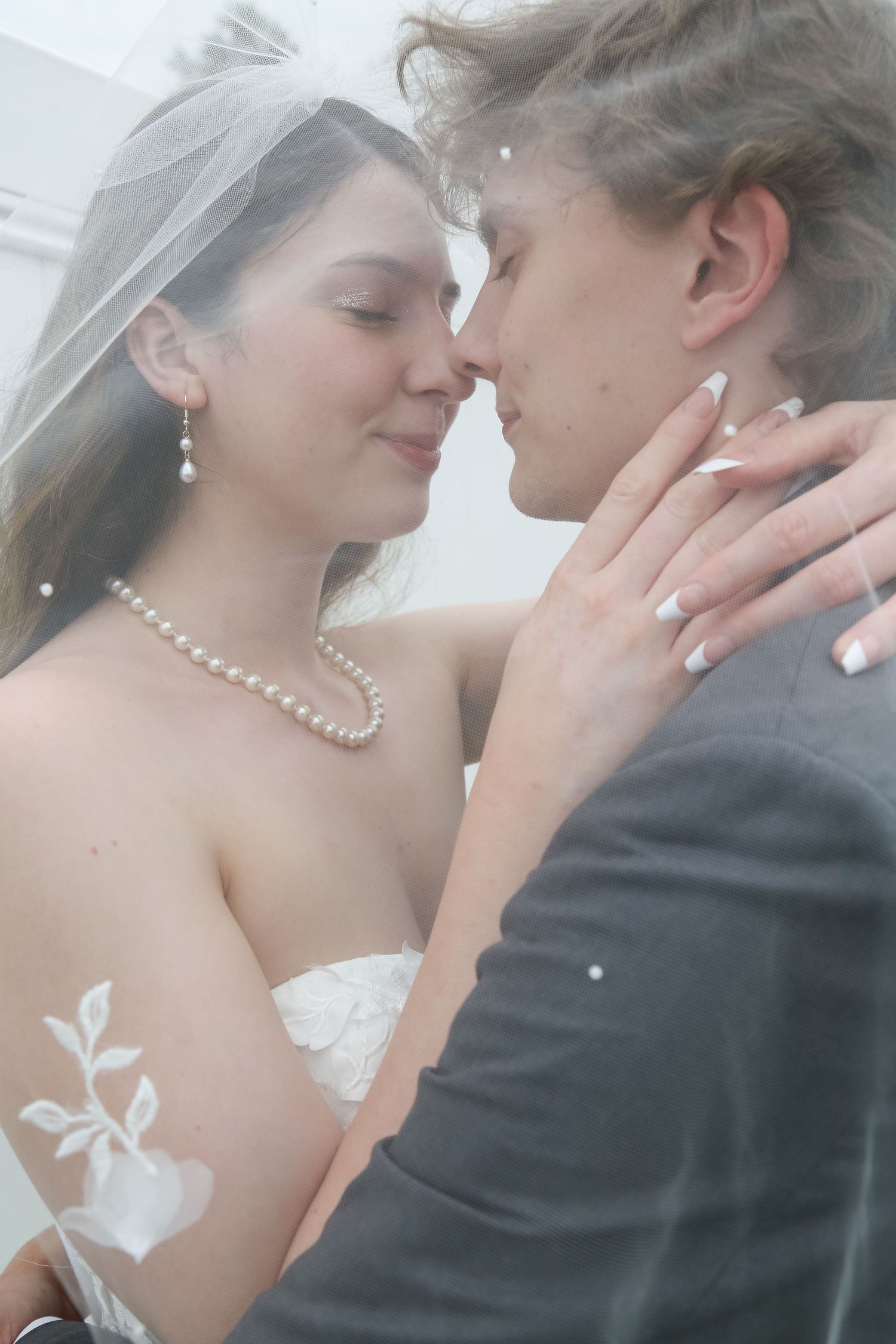 A tender wedding moment shows a couple in an intimate embrace, with the bride wearing pearls and a white veil.