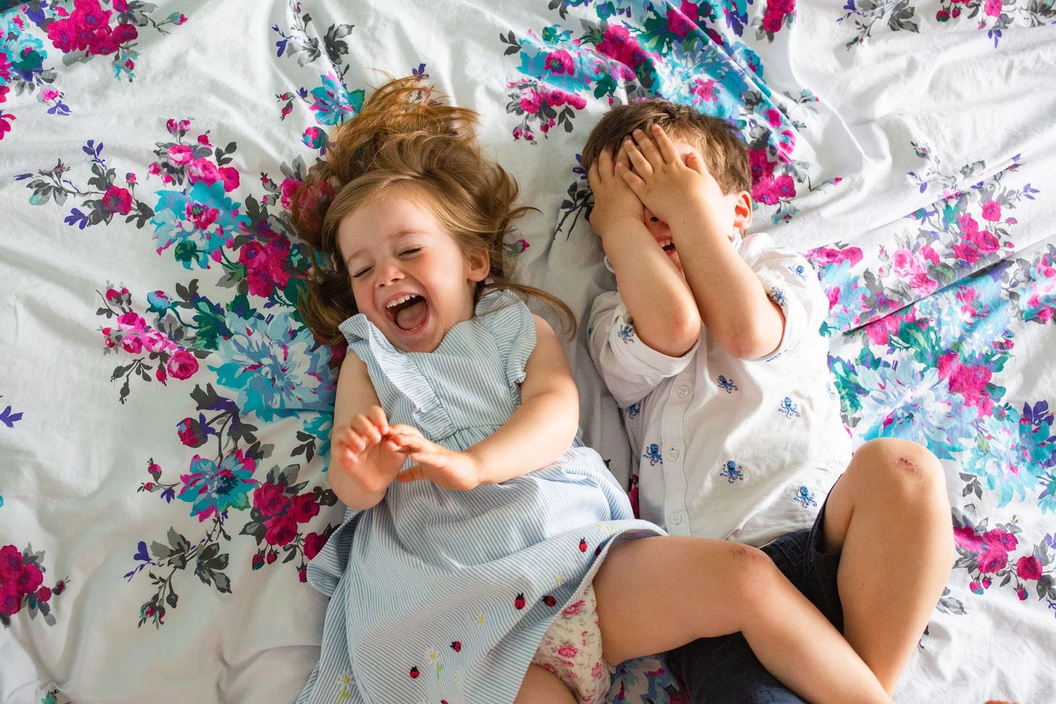 Tickles and giggles on the bed. Young children. Siblings.