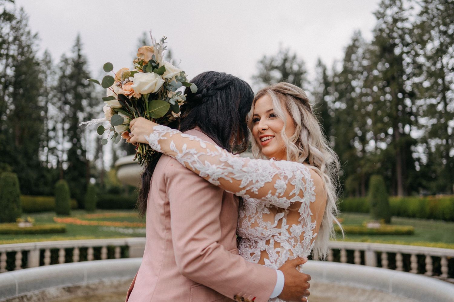 Joyful wedding moment with couple embracing outdoors holding a floral bouquet.