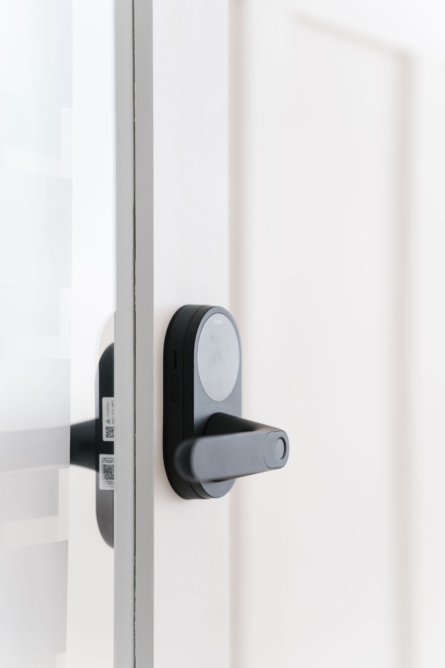 Modern black electronic door lock with handle mounted on white door frame in residential interior setting.