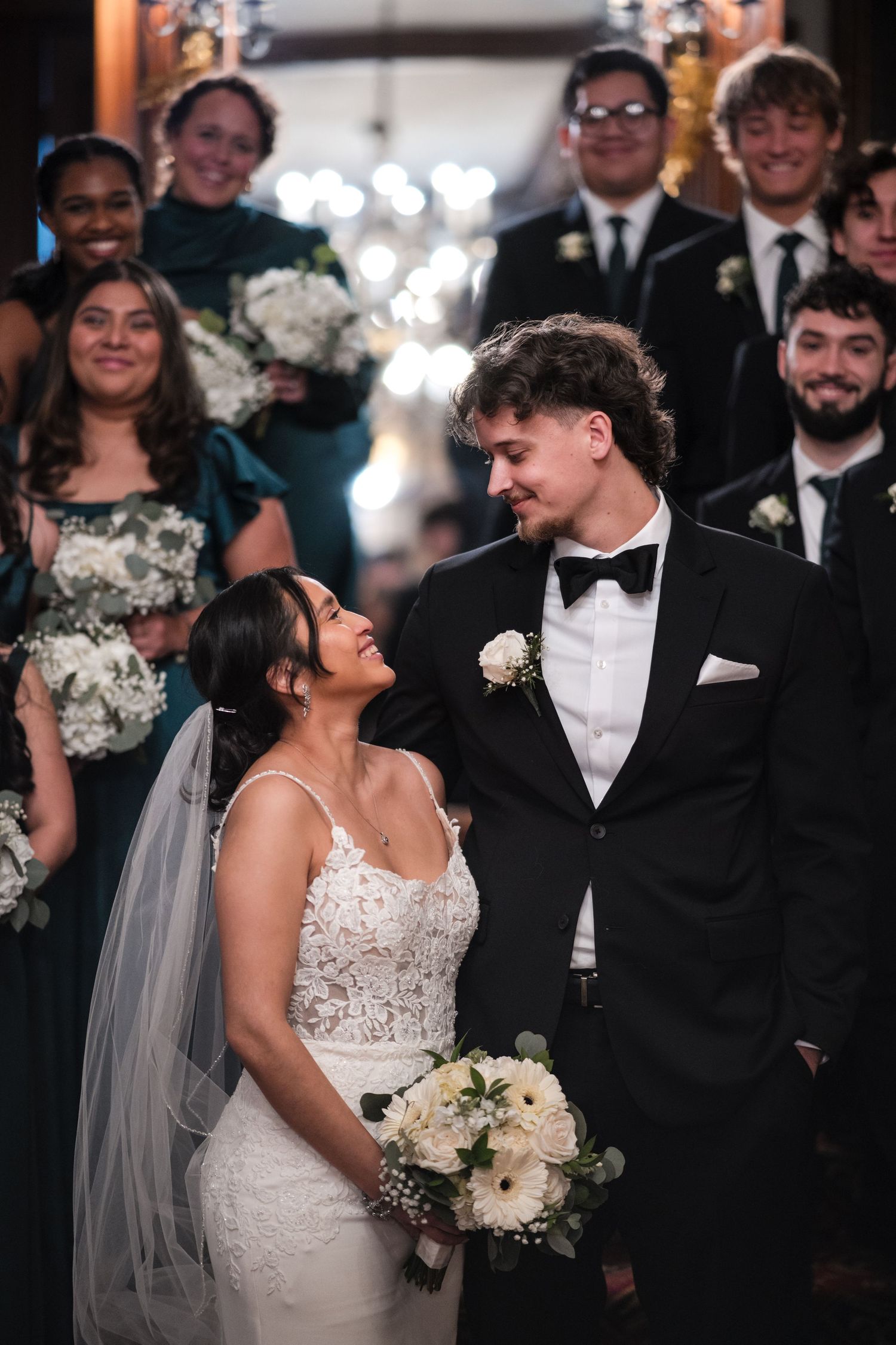 A beautiful wedding moment with the bride in lace gown and groom in black tuxedo sharing a loving glance.
