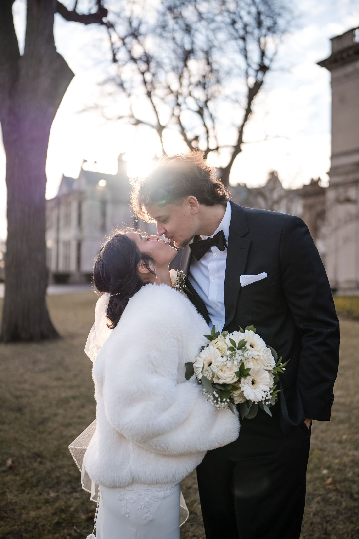 Tender moment between newlyweds as they embrace outside a historic building during winter.