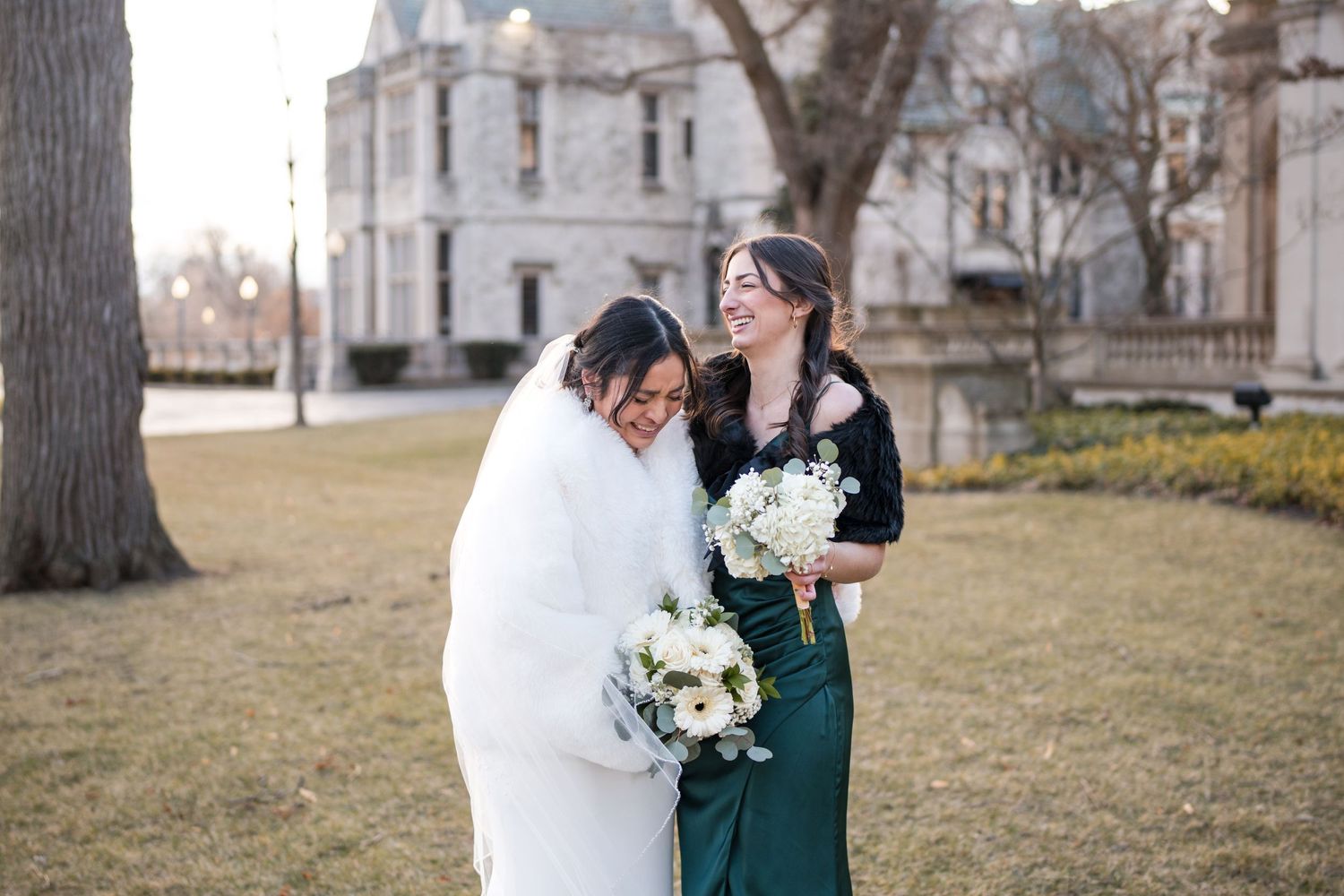 Wedding celebration outside elegant mansion with bridal party wearing black suits.