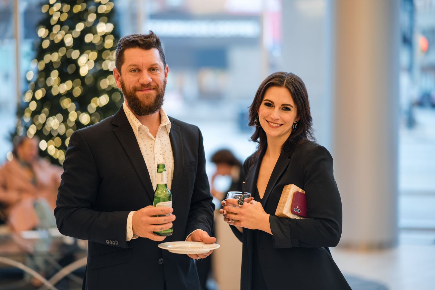 Wedding guests enjoying drinks at an indoor reception with holiday decorations and lighting.
