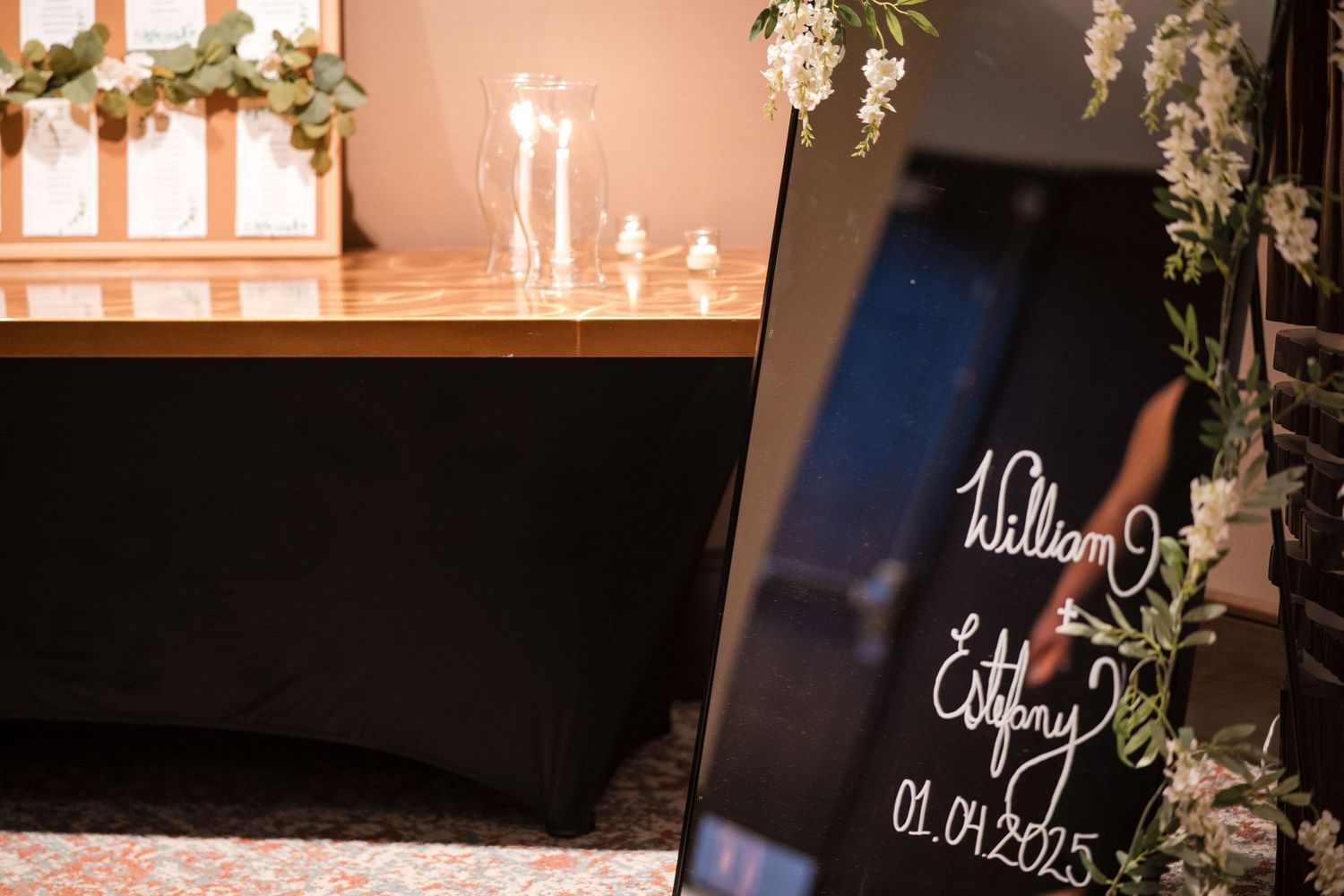Wedding date and details displayed on elegant black signage with candlelight decor.