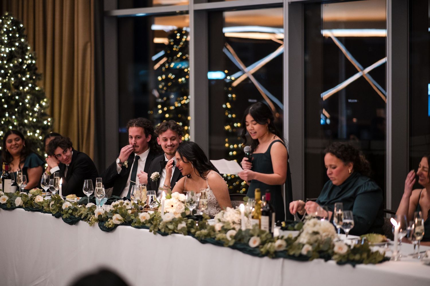 Wedding reception head table decorated with elegant floral arrangements and candlelight.