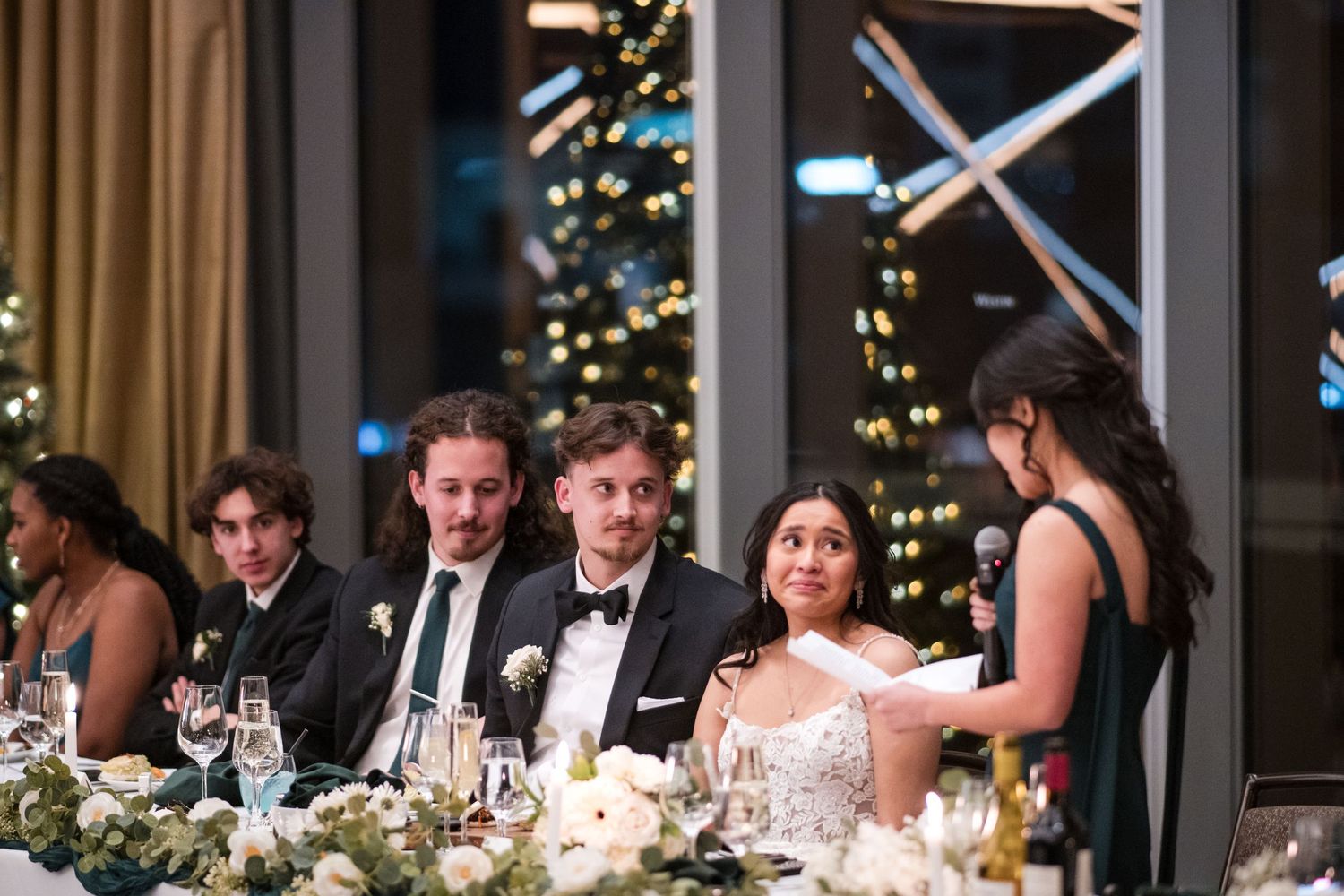 Elegant wedding reception with head table set against backdrop of city lights.