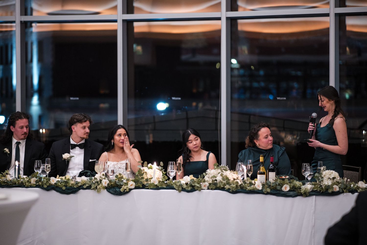 Wedding reception head table with elegant decor and city views.