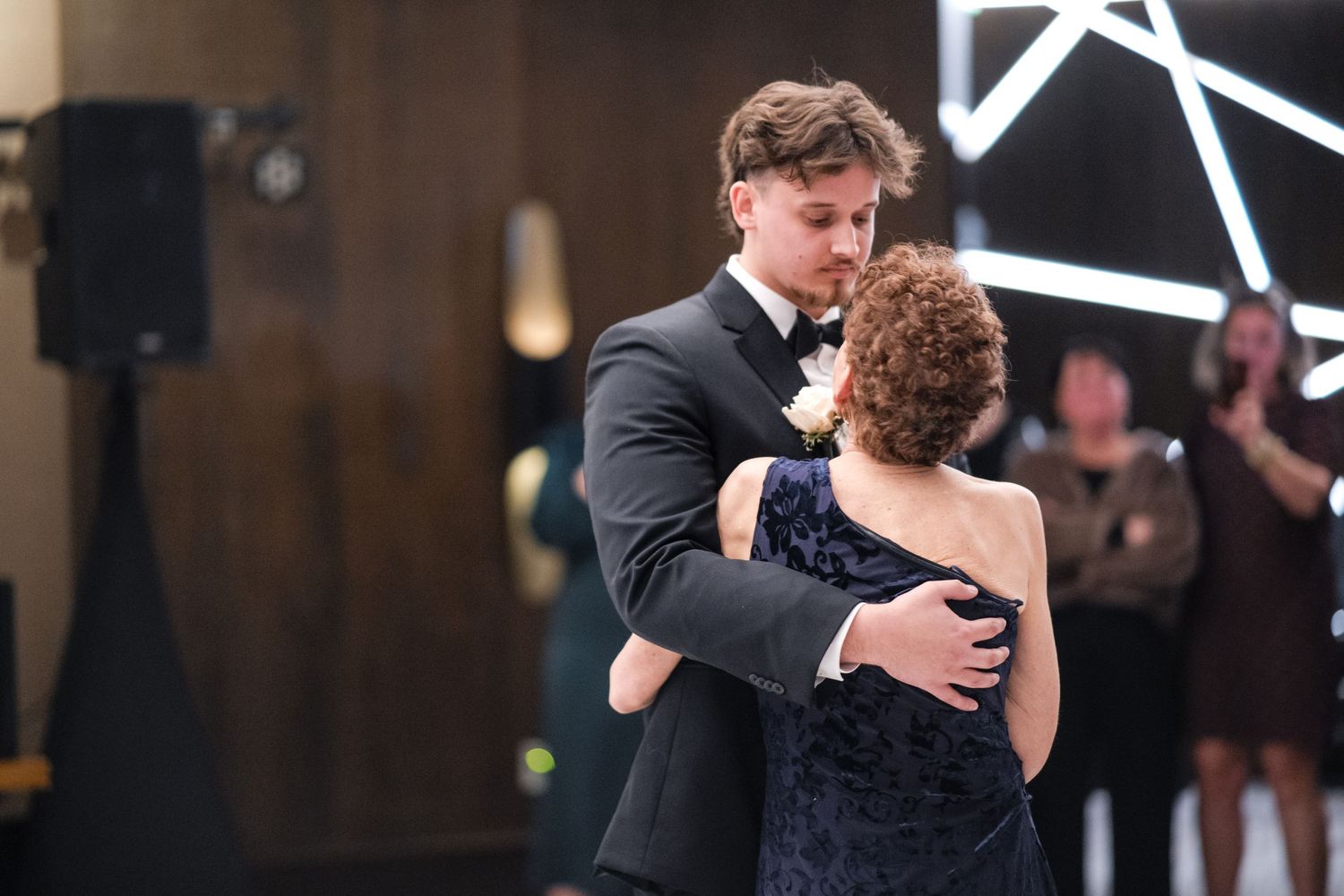 Couple shares an intimate dance moment under modern geometric lighting at their wedding reception.