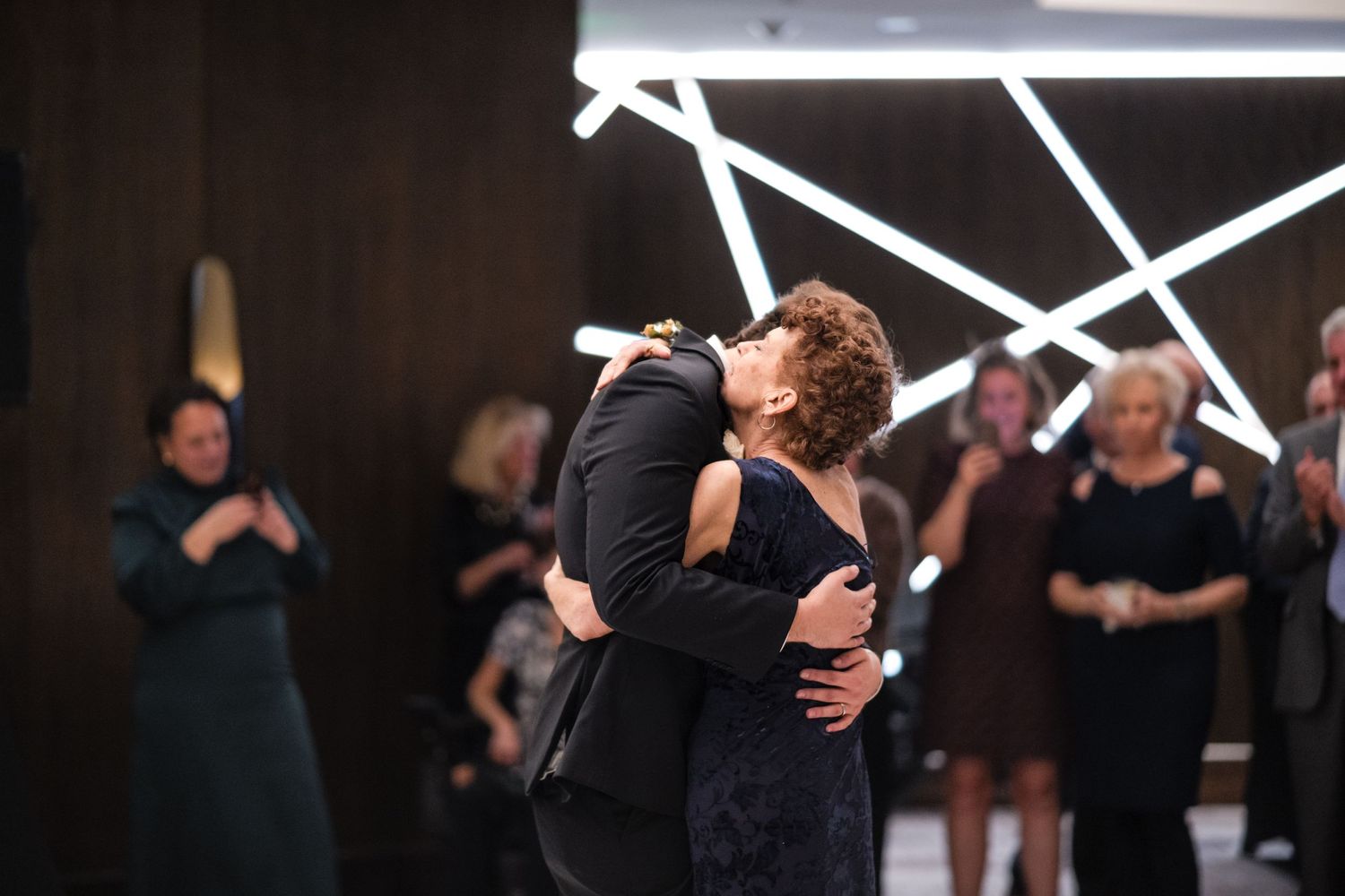 Couple shares a romantic dance while wedding guests look on at evening reception.
