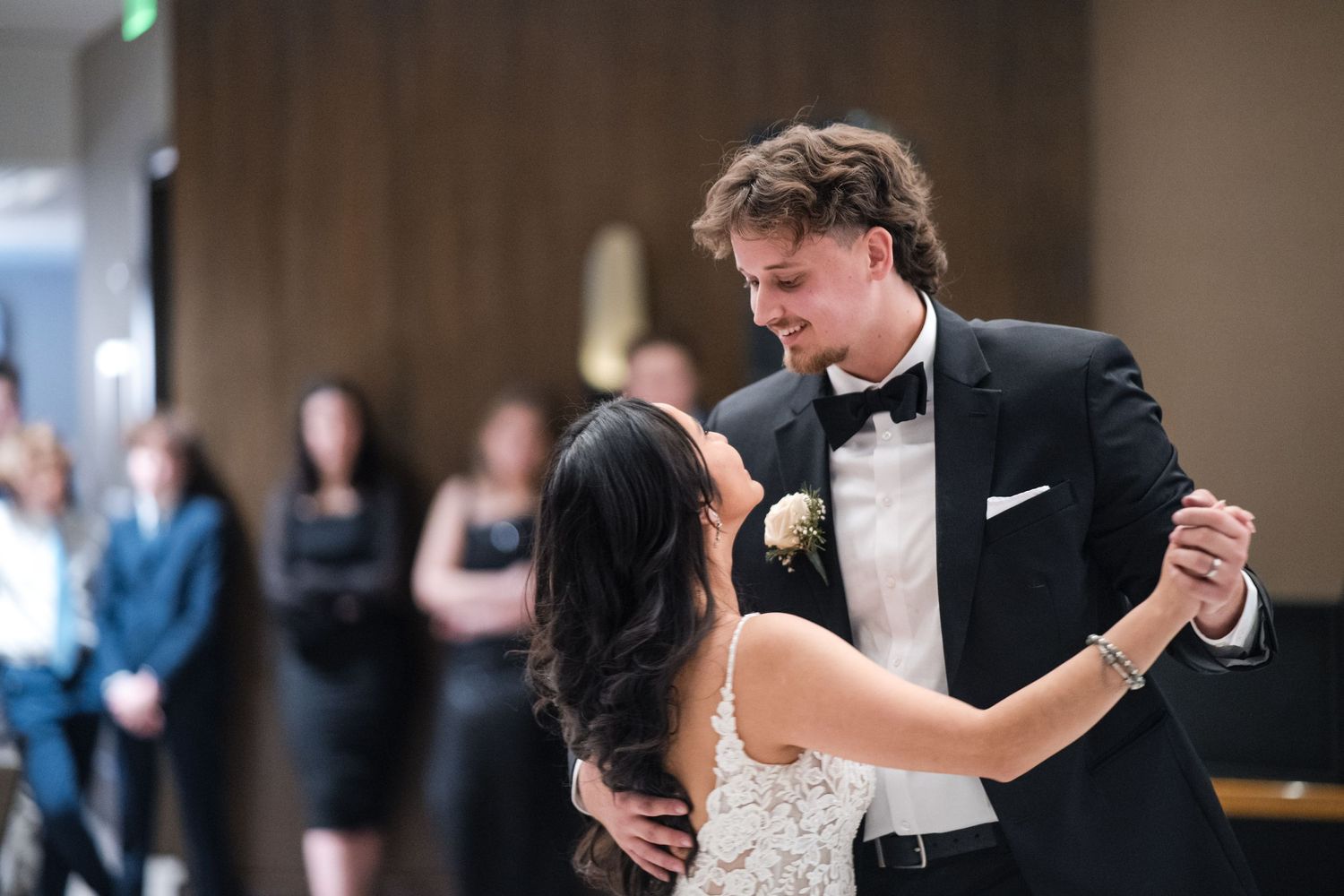 A couple dancing intimately at their wedding reception in formal attire.
