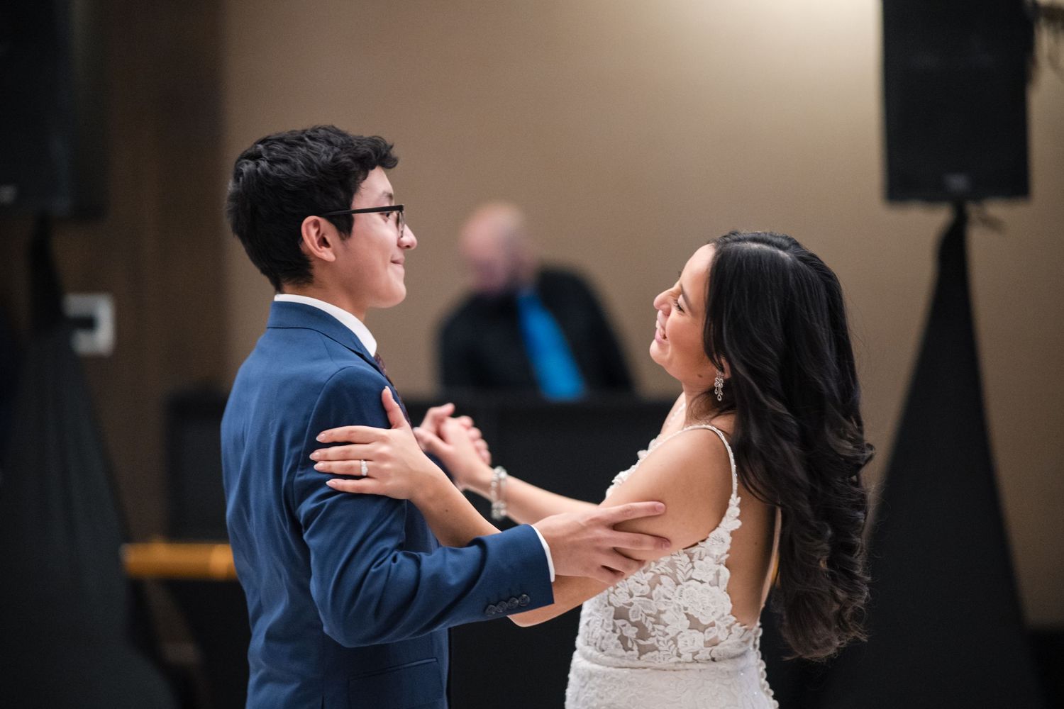 A couple smiles joyfully while dancing together at their wedding reception.
