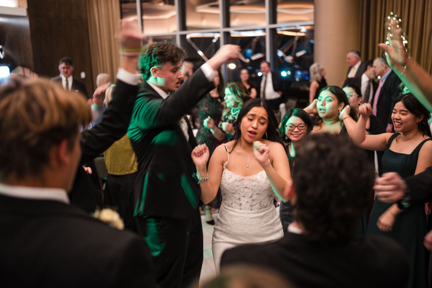 Wedding reception dance floor filled with joyful celebration and green-clad guests.