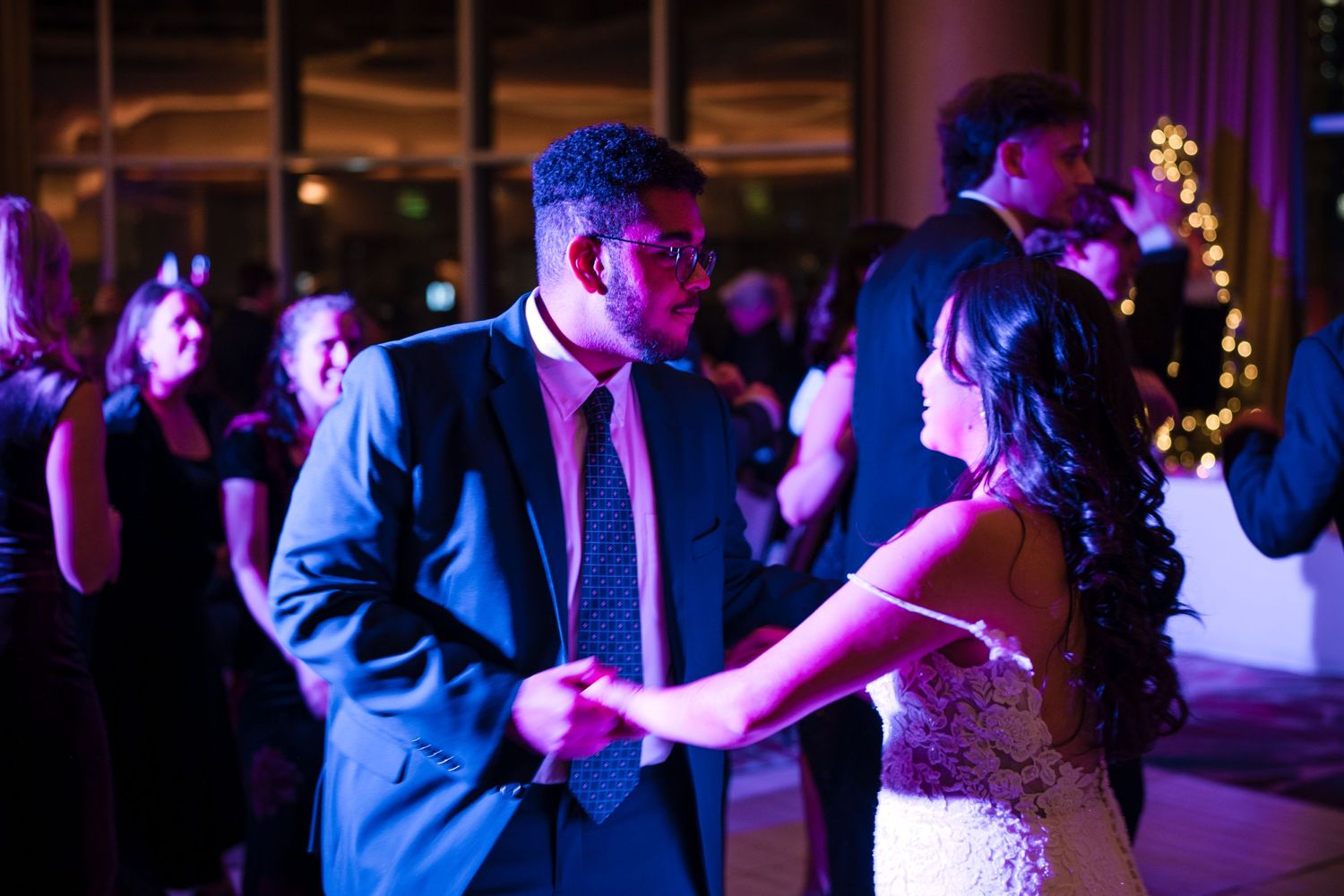Couple dancing at their wedding reception under purple mood lighting.