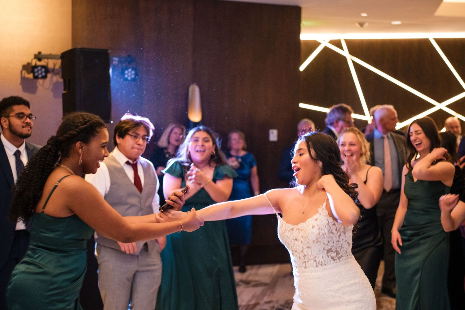 Wedding guests dancing and celebrating in formal attire at reception.