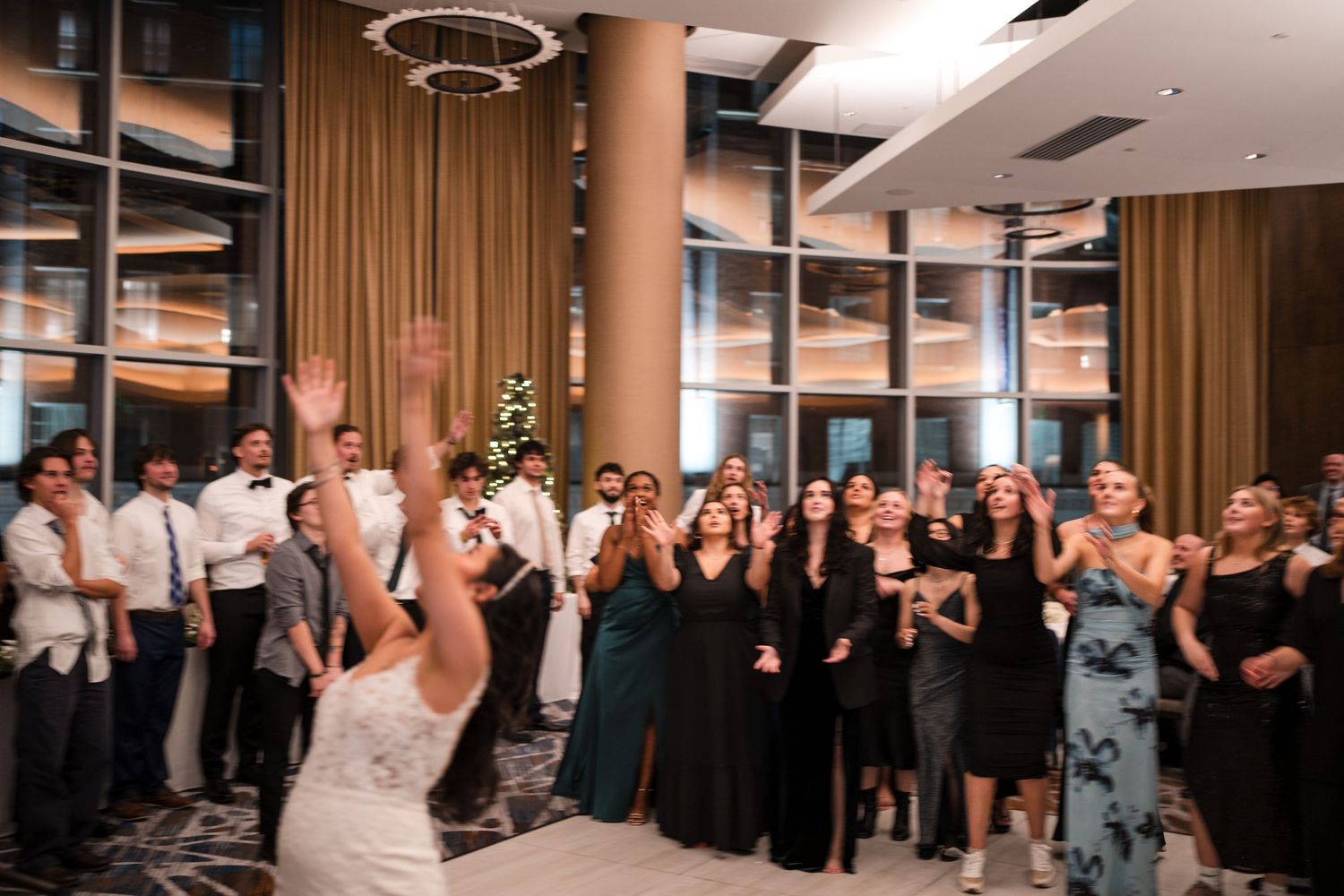 Wedding guests gather on a dance floor with formal attire and decorative lighting during a reception celebration.
