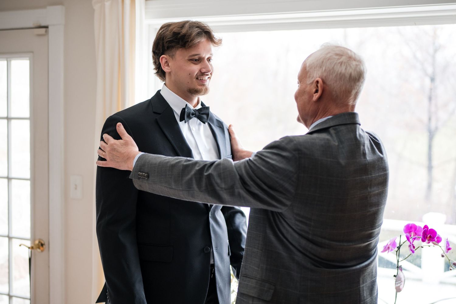 Two people having a conversation while one adjusts the other's formal attire.