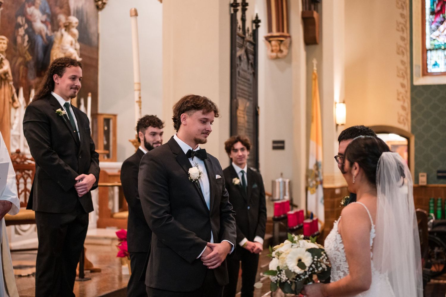 A wedding ceremony takes place at the altar of an ornate church with stained glass windows.