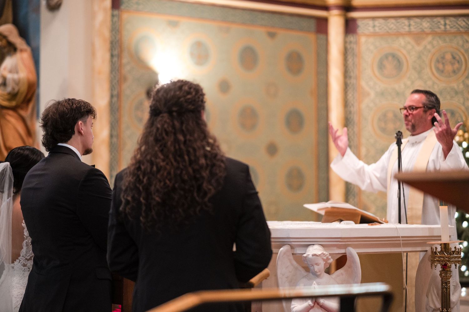A priest gestures while conducting a wedding ceremony at a church altar.