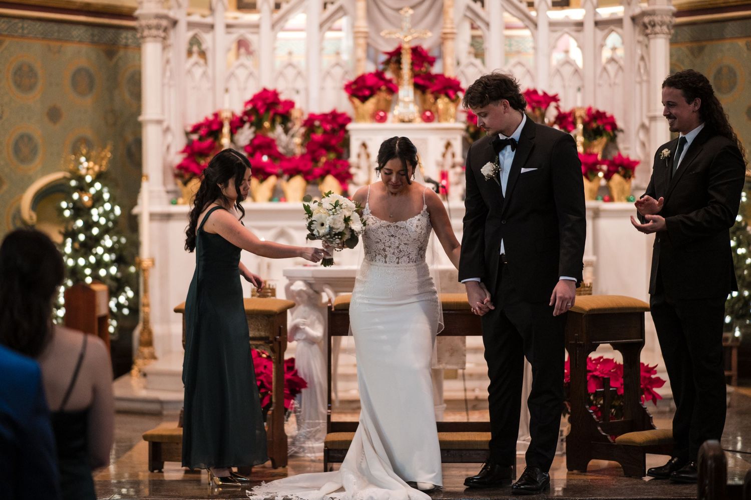 Wedding ceremony in an ornate church with pink floral arch decorations and twinkling lights.