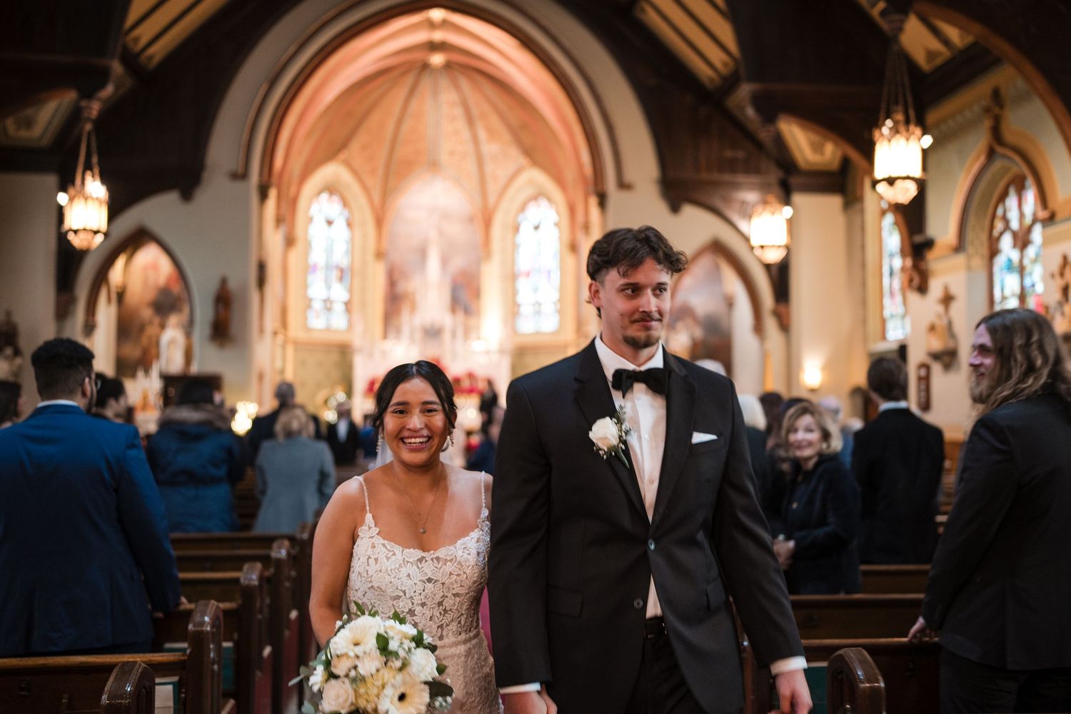 Joyful couple walking down the aisle of a traditional church with stained glass windows.