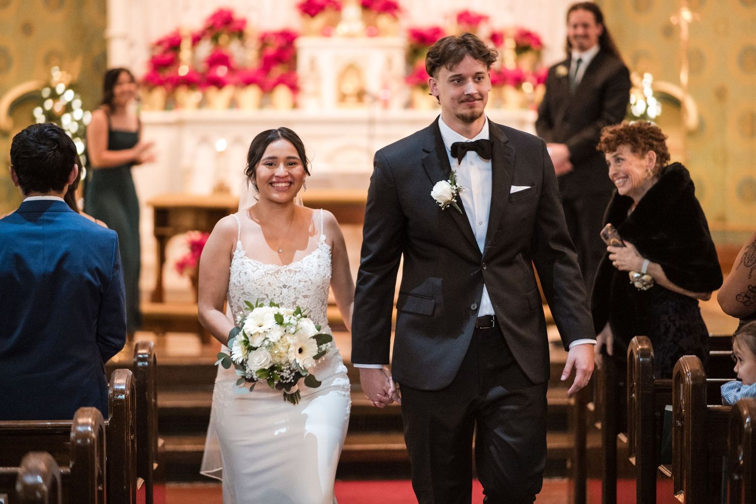 A couple walking down the church aisle after their ceremony with joyful expressions.