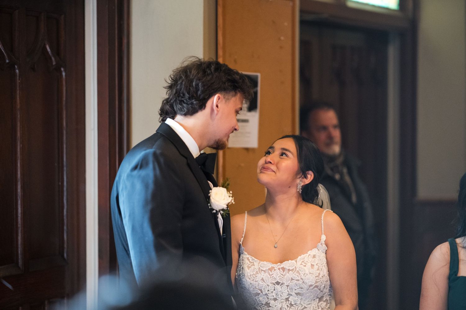 Candid moment between newlyweds sharing a laugh in a church hallway.