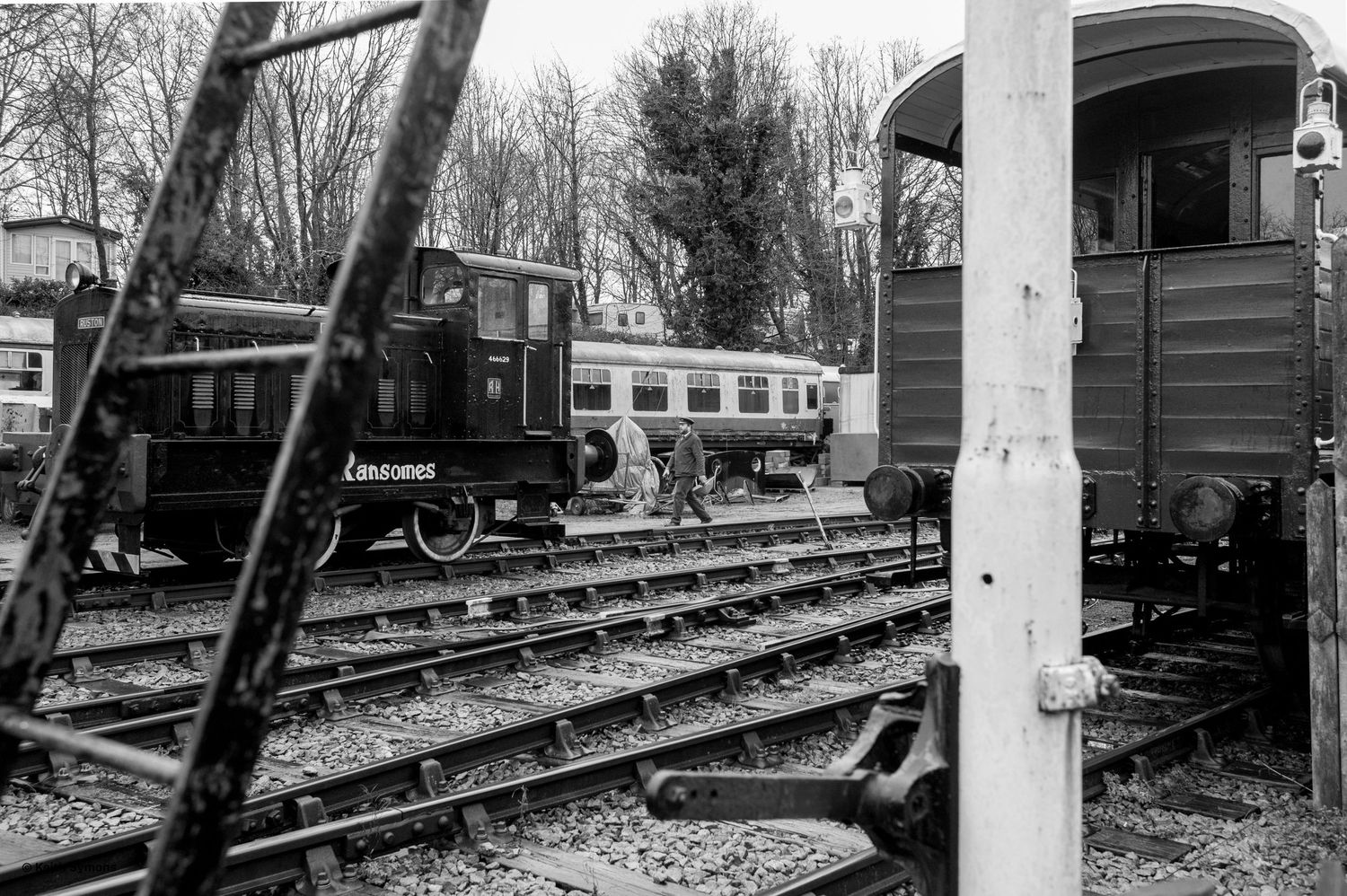 Black and white photograph of vintage railway cars and a locomotive on multiple tracks at a train yard.