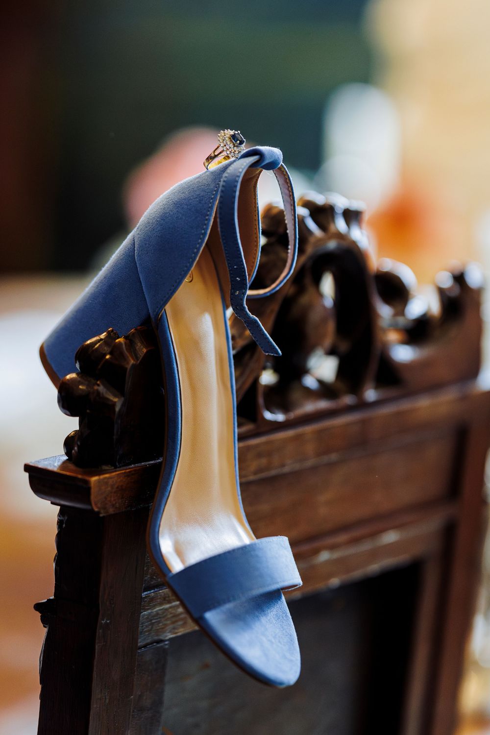 A powder blue wedding heel hangs on an ornate wooden church pew during a ceremony.